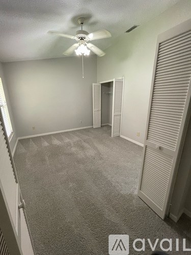 A room with a carpeted floor and a ceiling fan.
