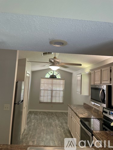 A kitchen with a fan on the ceiling and a microwave on the counter.