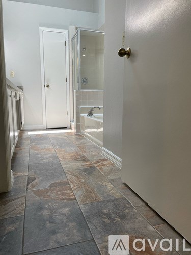 A bathroom with a tiled floor and a shower area.