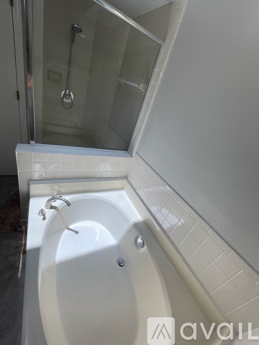 A white bathtub with a glass shower door.