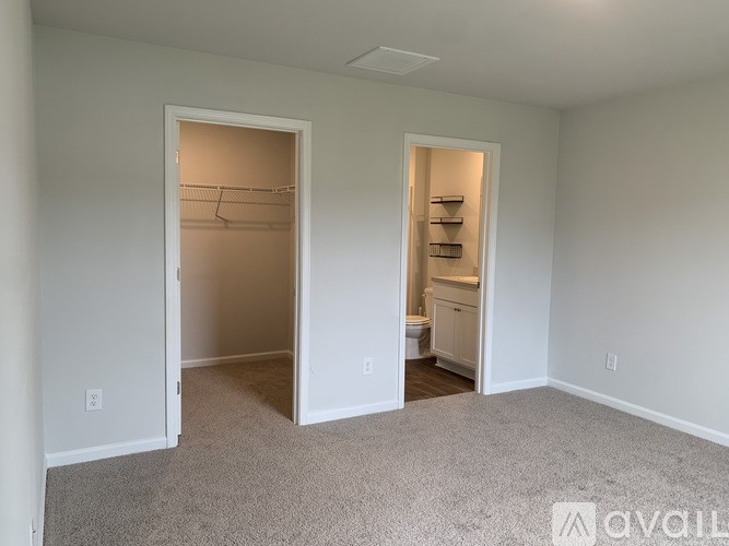 A room with a carpeted floor and two open doors leading to other rooms.