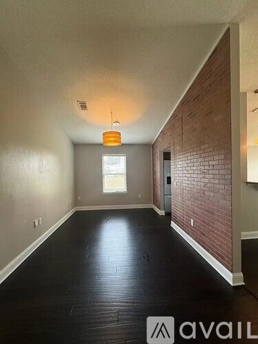 A room with a brick wall and wooden floor.