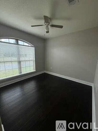 A room with a ceiling fan and a window with blinds.