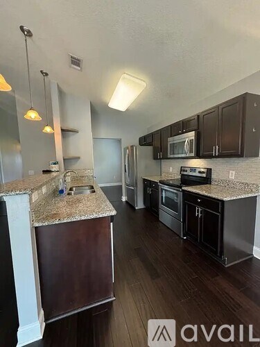 A kitchen with dark wood floors and granite countertops.