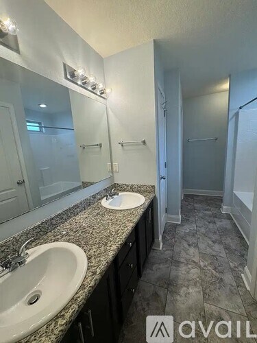 A bathroom with granite countertops and two sinks.