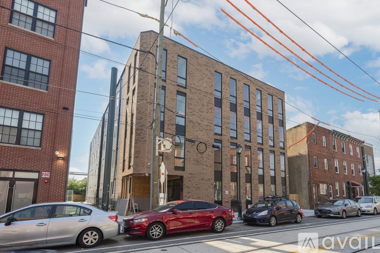 A red car is parked on the side of a street in front of a building.