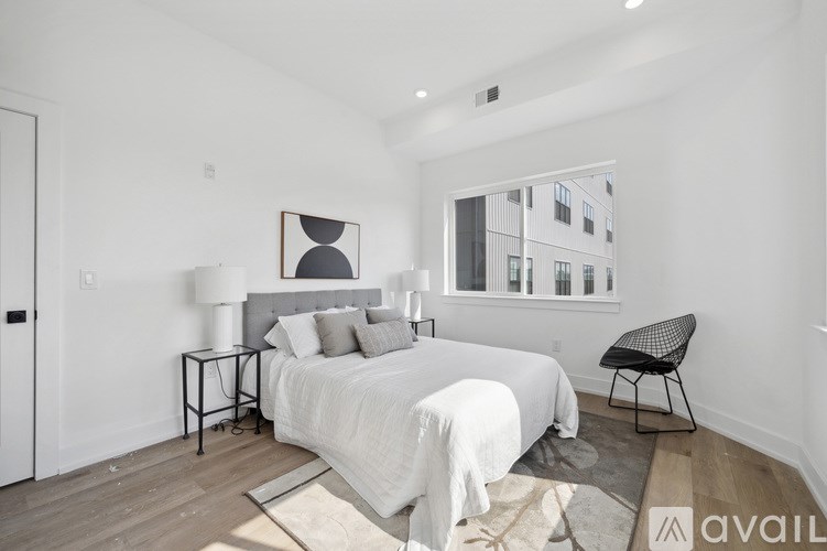 A bedroom with a large bed, a chair, and a picture on the wall.