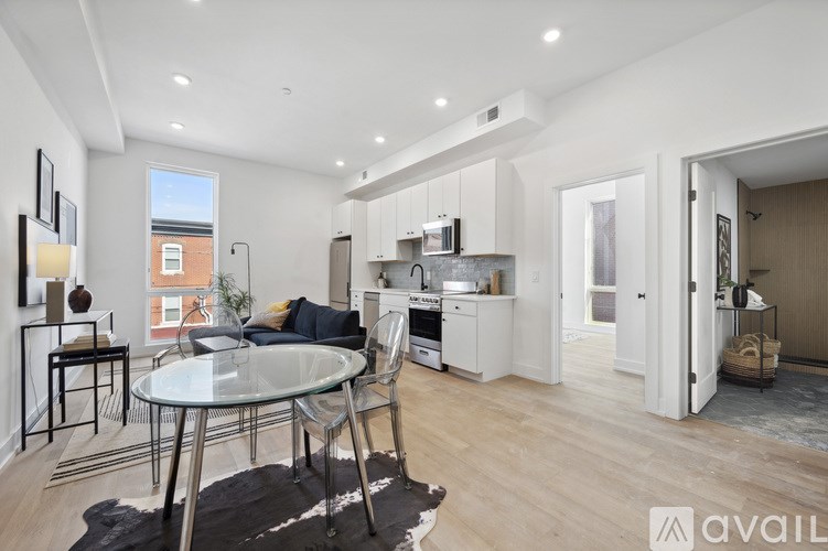 A modern kitchen with a glass table and chairs, and a dining area with a rug.