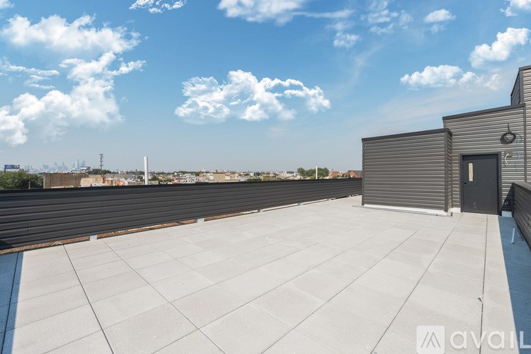 A rooftop with a closed black door and a metal railing.