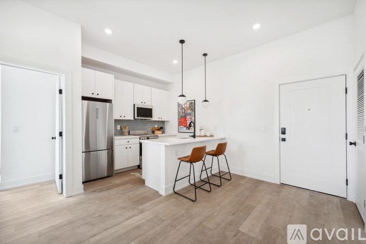A kitchen with a white island and bar stools.