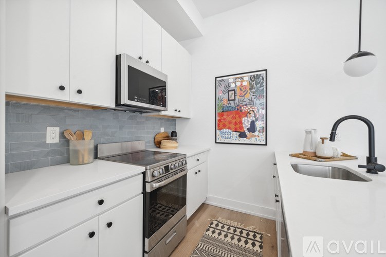 A kitchen with white cabinets and a grey backsplash.