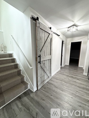 A wooden staircase with a metal railing leads to a door.