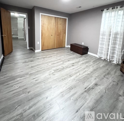 A room with wooden flooring and a bench against the wall.