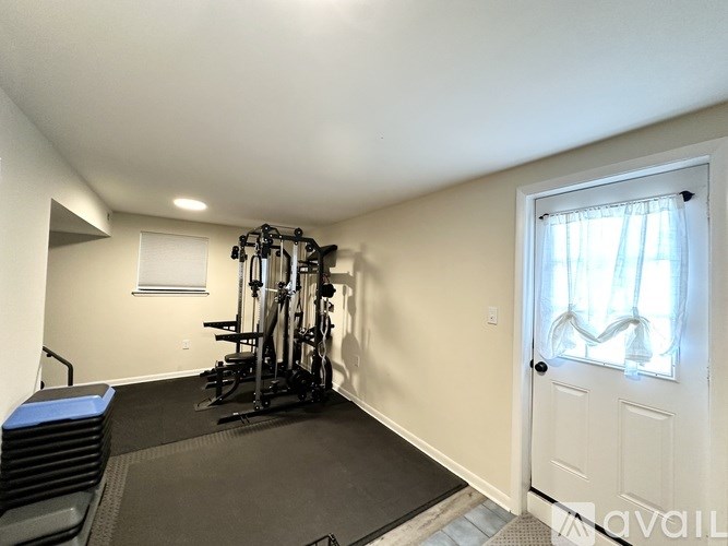 A room with a treadmill, exercise bike, and weights.