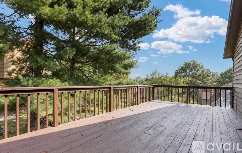 A wooden deck with a railing and trees in the background.