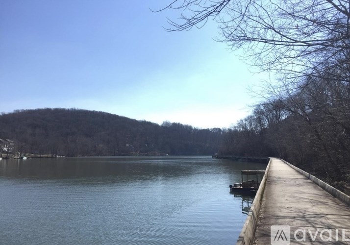 A calm lake with a dock extending into the water and trees on the opposite shore.