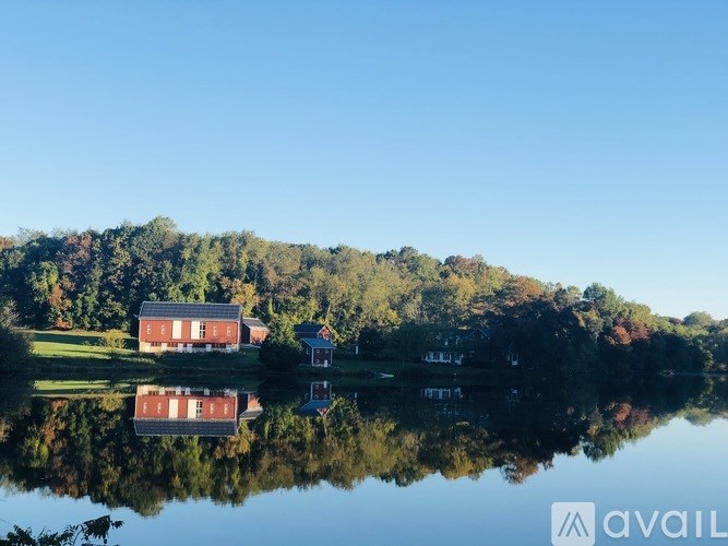 A house is reflected in the water in front of a forest.