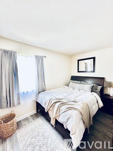 A bedroom with a large bed and a wicker basket on the floor.