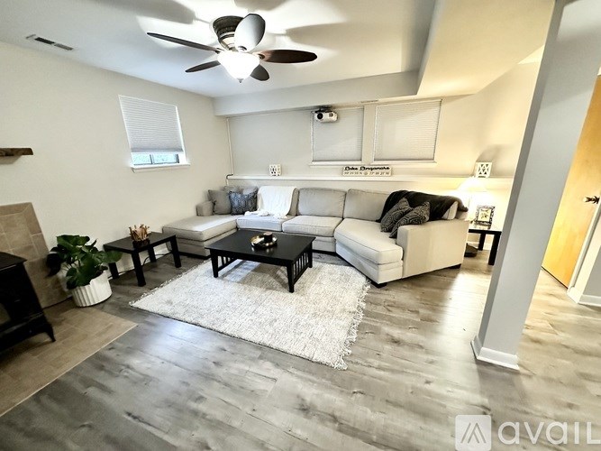 A living room with a white couch, a black coffee table, and a ceiling fan.