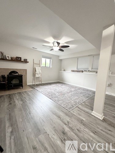 A spacious room with a fireplace and a fan on the ceiling.