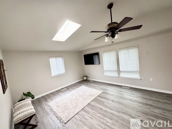 A room with a ceiling fan and a rug on the floor.