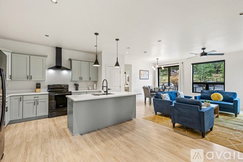 A modern kitchen with a large island and a living room with a couch and chairs.