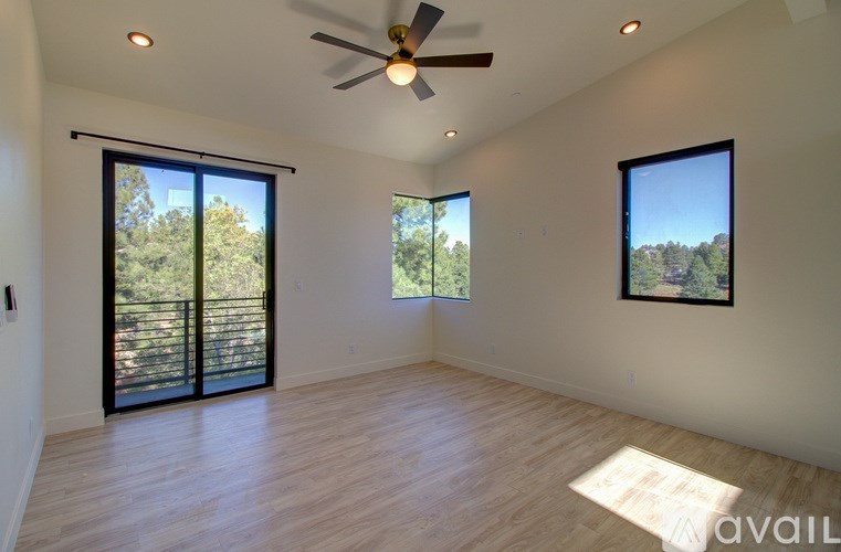 A room with a ceiling fan and two windows.