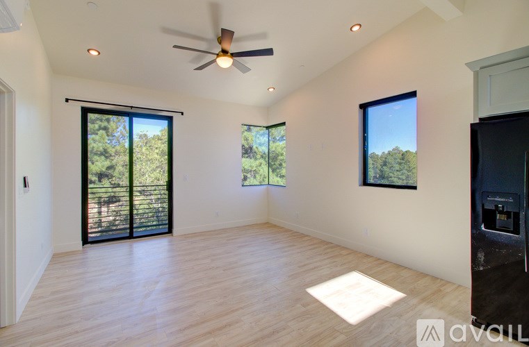 A spacious room with a ceiling fan and sliding glass doors leading to a backyard.