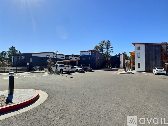 A sunny day at a parking lot with a white truck and a building with a sign that says "AVAIL".