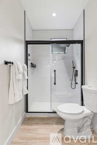 A white toilet in a modern bathroom with a walk-in shower.