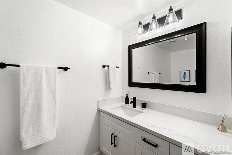 A white bathroom with a mirror, sink, and towel rack.