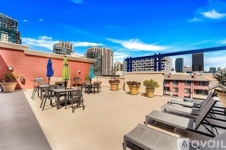A rooftop patio with chairs and umbrellas overlooking a city skyline.