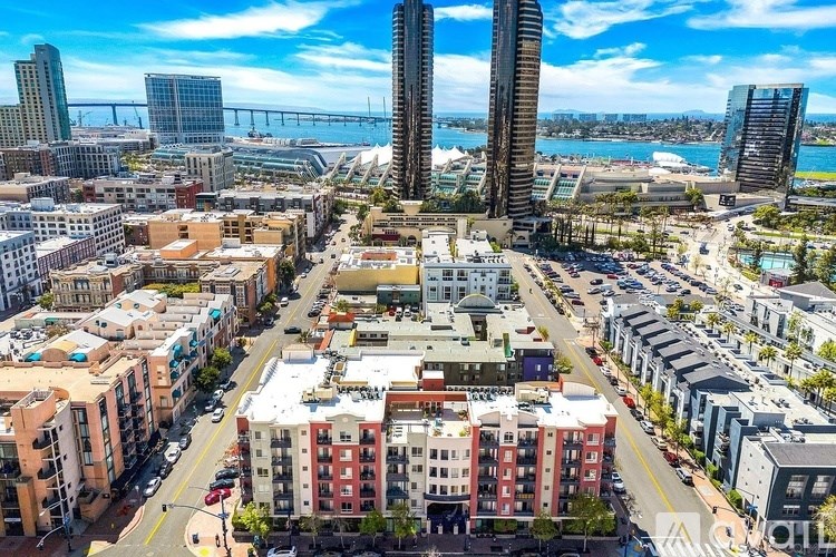 A cityscape with a mix of residential and commercial buildings, a bridge in the background, and a clear sky.