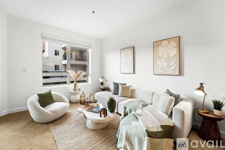 A living room with a white couch, a white chair, and two framed pictures on the wall.