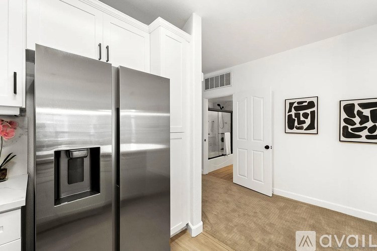 A kitchen with a stainless steel refrigerator and white cabinets.