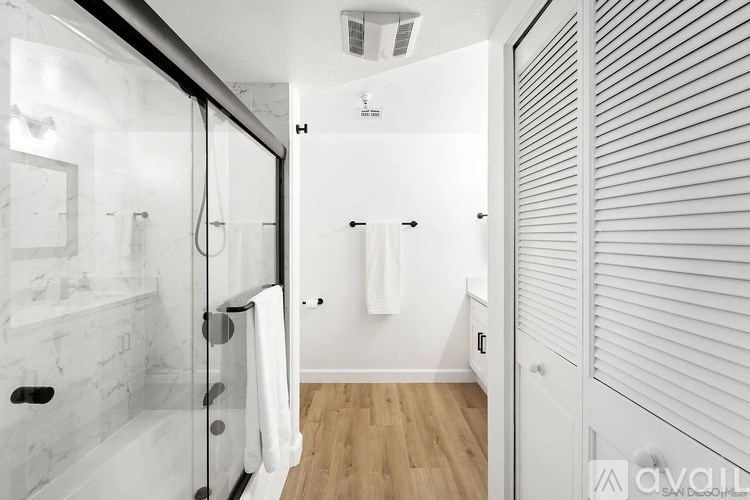 A white bathroom with a walk in shower and a towel rack.