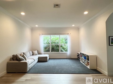 A living room with a grey sofa and a large window.