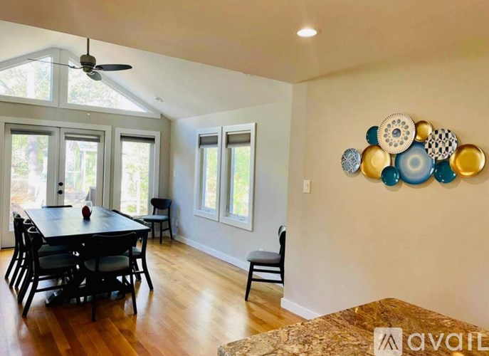 A dining room with a table and chairs and a fan on the ceiling.