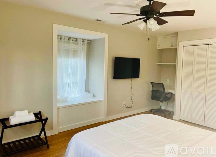 A bedroom with a large bed, a television, and a chair.