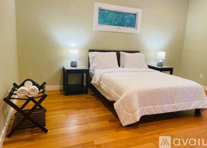 A bedroom with a large bed and a wooden chair with towels on it.