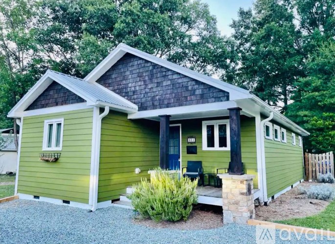 A green house with a porch and a small garden in front.