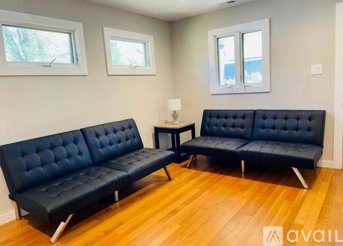 A living room with two black tufted sofas and a small table.