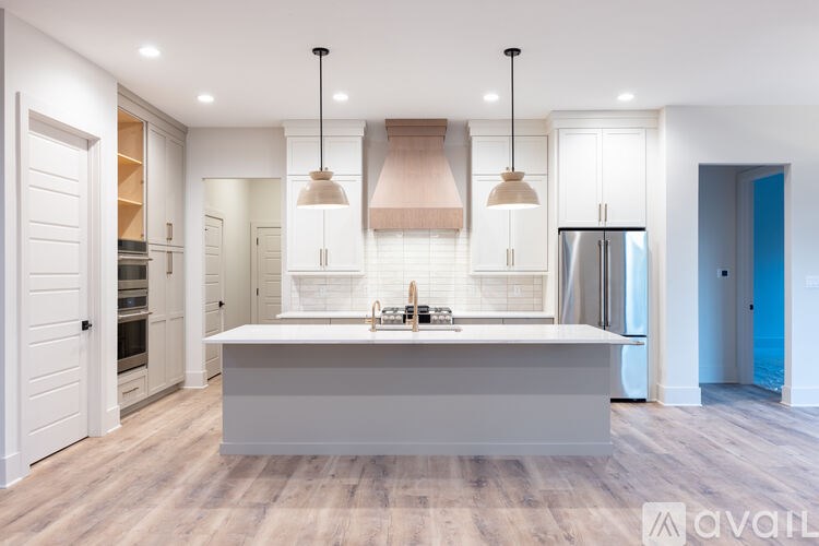 A modern kitchen with a large island and pendant lights.
