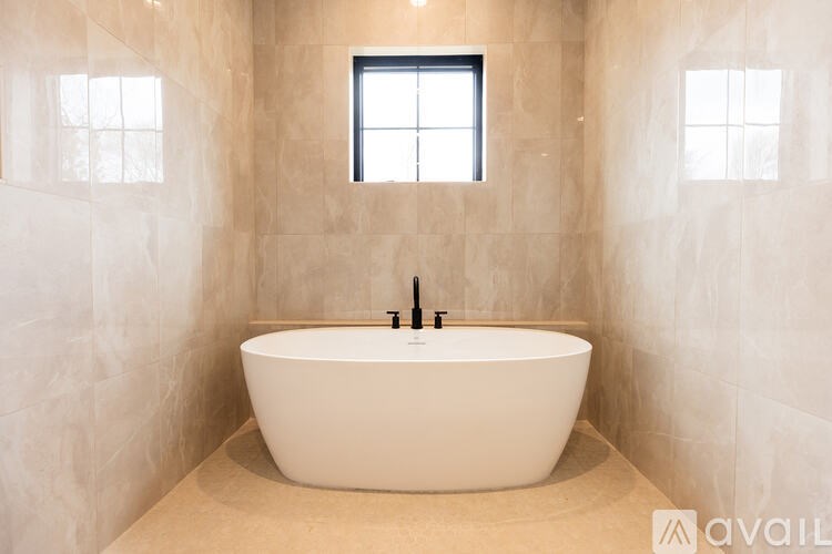 A white bathtub is in a bathroom with a window.