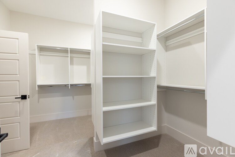 A white shelving unit in a room with a door on the left.