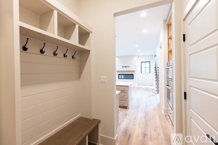 A hallway with a bench and coat hooks on the wall.