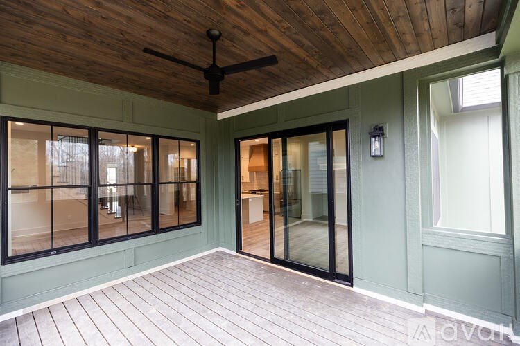 A room with a wooden ceiling and floor, a ceiling fan, and a glass door leading to another room.