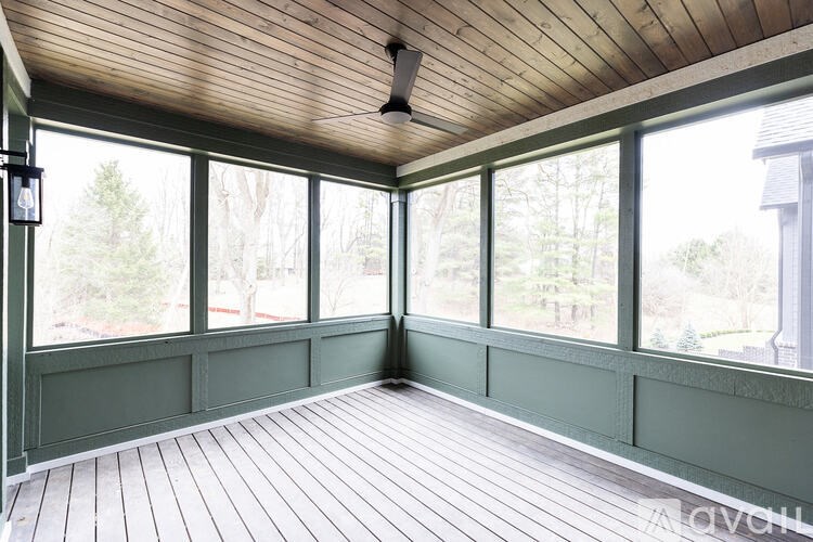 A sunroom with wooden floors and a ceiling fan.