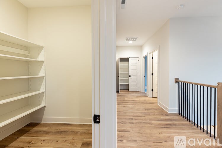 A hallway with a white door and a balcony with a black railing.