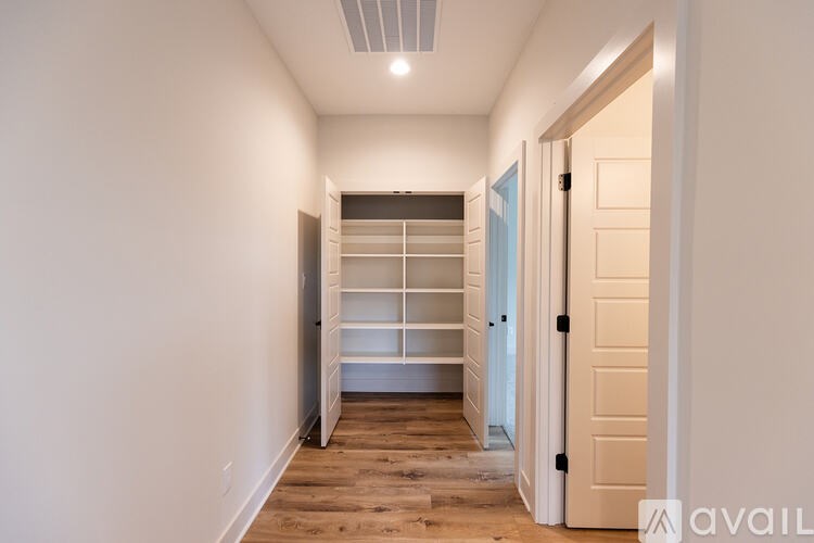 A hallway with a white door on the right and a white wall on the left.